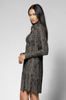 A woman modeling a long-sleeve, high-neck mini dress with a textured, vertically striped pattern in black and gray, photographed against a neutral light gray studio background.