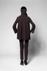 A model viewed from the back wearing a dark brown tailored blazer and matching slim trousers with black heels, set against a light gray studio background.