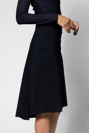A model wearing a black long-sleeve midi skirt with a flared A-line silhouette, paired with a matching dark top, shown against a neutral gray studio background.