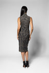 A woman viewed from the back wearing a sleeveless, high-neck top with matching knee-length skirt with a textured black and gray pattern, paired with black ankle boots, against a light gray studio background.