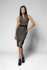 A woman modeling a sleeveless, wrap-style midi top and skirt with a textured black and gray pattern, a black waistband, and a side slit, paired with black high heels against a light gray studio background.