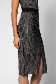 A model wearing a sleeveless black midi skirt with a textured, vertically pleated pattern and a high side slit, shown against a light gray studio background.
