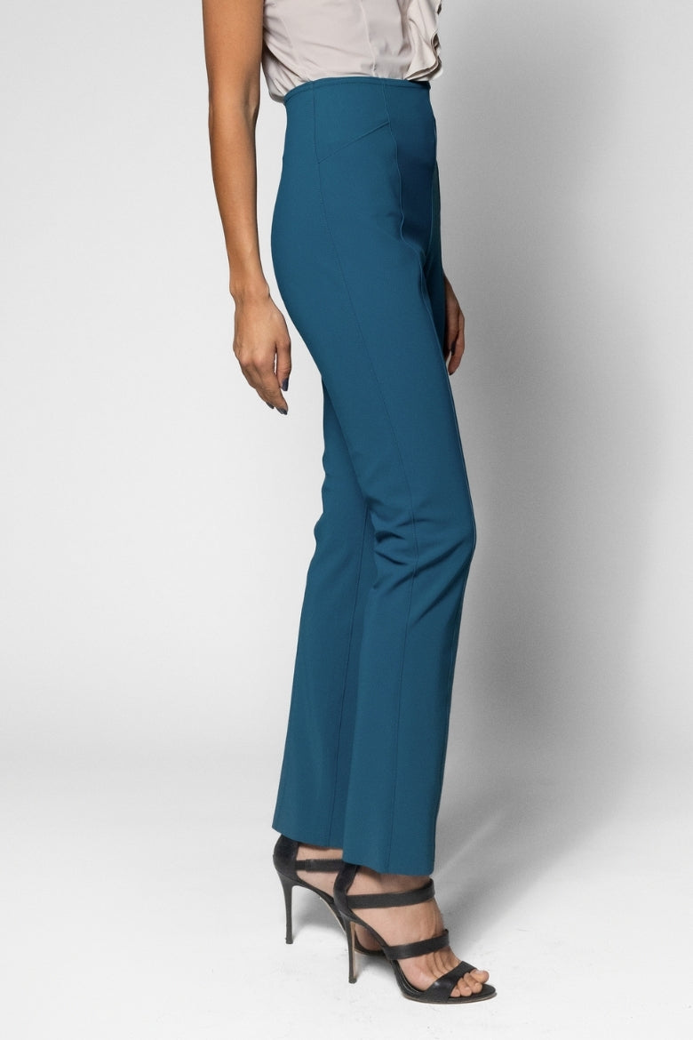 A model wearing high-waisted, wide-leg teal blue trousers paired with black strappy high-heeled sandals, shown from the waist down against a light gray studio background.