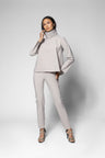 A model wearing a light gray two-piece set consisting of a long-sleeve mock-neck top and matching slim-fit pants, paired with leopard-print high heels, against a light gray studio background.