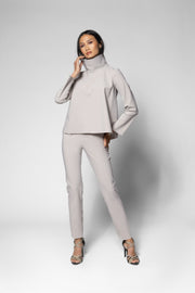 A model wearing a light gray two-piece set consisting of a long-sleeve mock-neck top and matching slim-fit pants, paired with leopard-print high heels, against a light gray studio background.