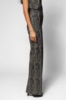 A side view of a model wearing a textured, dark gray and black wide-leg pant against a light gray studio background.