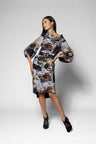 A model wearing a knee-length floral print top with dramatic balloon sleeves and a matching belt paired with a skirt in the same print, posed against a light gray studio background.