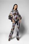 A model wearing a matching two-piece floral print set consisting of a wide-sleeved top and matching trousers, styled with black strappy high-heeled sandals against a light gray studio background.